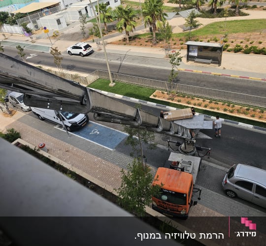 מנוף מעביר קופסה לרחוב עם מכוניות ואנשים